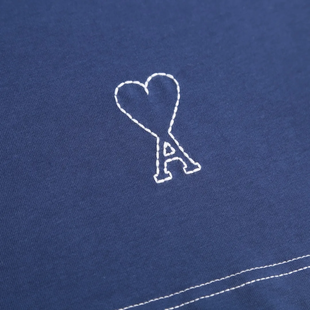 AMI Love A Embroidered Short Sleeve Fabric Selection: High-count pure cotton is selected, with moderate weight and natural drape. The cotton fiber itself has good moisture absorption and breathability, which can quickly absorb sweat and dissipate it outwards. At the same time, it feels soft and delicate, and it is non-itchy when worn next to the skin. After the pre-shrinking process, the washing shrinkage is greatly reduced, and it is not easy to deform after repeated machine washing. Craftsmanship: 1: The advanced computing system of imported embroidery machines is used to depict the contour lines of the love A pattern. White embroidery thread and Tibetan Blue fabric form a soft contrast, with neat edges, no skipping lines, and no burrs. The pattern is full and three-dimensional, and the texture is delicate. 2. Make dark embroidery of letters of the same color on the back neckline, using embroidery threads of the same color as the fabric, which is low-key and not obtrusive, and does not destroy the overall simple style. The back of the embroidered product is flat and has no bulges, and will not irritate the skin, taking into account both beauty and wearing comfort. Sewing details: 1: The collar, cuffs, hem, and shoulder lines are all made of contrasting topstitching and double-turn craftsmanship. The neatly routed threads form a sharp contrast with the Tibetan Blue fabric and outline the outline of the clothes. 2: The internal seams of the clothes are all treated with overlocking technology, without excess burrs or threads, and the details are clean and tidy; the hem and cuffs are made with double-folding stitching technology, and the edges are smooth and not frizzy to avoid curling and curling when wearing. Accessories: One-to-one customized three-standard Size: S M L XL Style No. D 292